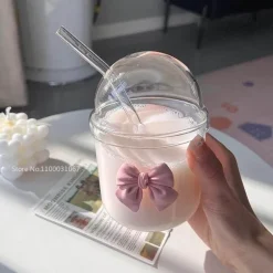 Rosa Kaffeetasse aus Glas mit Fliege, Deckel und Strohhalm – süßes Trinkgeschirr