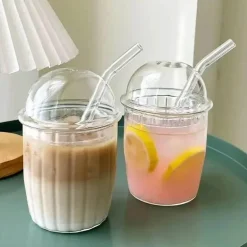 Rosa Kaffeetasse aus Glas mit Fliege, Deckel und Strohhalm – süßes Trinkgeschirr